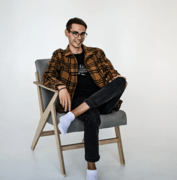 male designer wearing glasses and brown jacket with a smile on his face